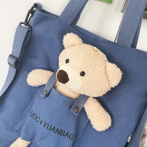 Vista detallada del bolso cruzado de lona azul con un adorable osito de peluche integrado.