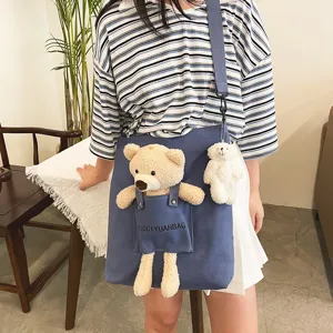 Bolso cruzado de lona con peluche de osito lindo y vista detallada del bolsillo de tela.