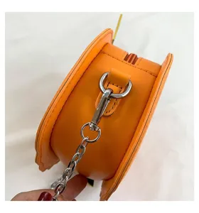 Detail view of the orange pumpkin crossbody bag, showing side zipper and metal chain link.