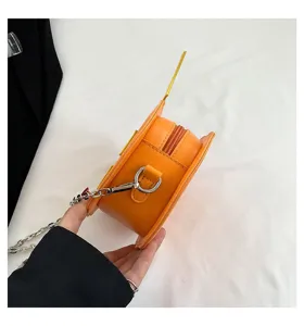 Close-up detail of the orange novelty pumpkin crossbody bag showing zipper and metal chain strap.