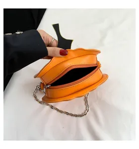 Closeup of orange pumpkin crossbody bag, showing zipper detail and metal chain strap.