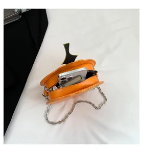 Orange pumpkin shoulder bag detail showing interior space and silver chain strap design.