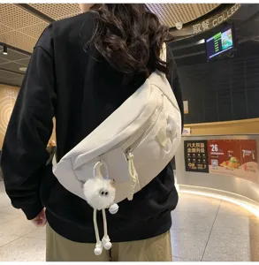 Vue détaillée du sac poitrine en nylon écru, avec charm en peluche mignon pour un style quotidien.