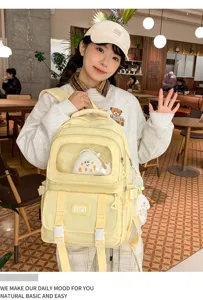 Casual yellow canvas backpack with clear front pocket, cute plush pendant, large capacity.