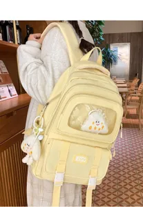 Detailed view of light yellow multi-pocket canvas backpack with transparent window and cute plush.