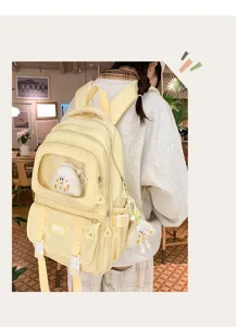 Detailed shot of light yellow campus student backpack with transparent window and cute pendant.