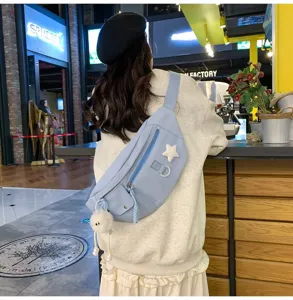 Vue détaillée du sac de poitrine en nylon bleu clair avec pendentif étoile et pompon duveteux.