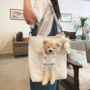 Vista detallada del lindo bolso de lona con bolsillo de oso de peluche y mini colgante.