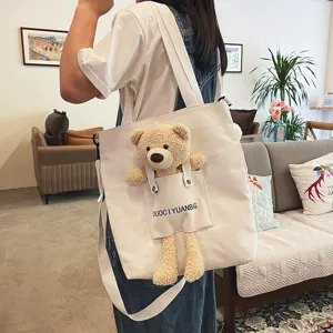 Detalle de linda bolsa de lona con muñeco de peluche 3D juguetón en el bolsillo frontal.