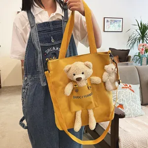 Vista detallada del bonito bolso de lona con osito de peluche y correa para el hombro.