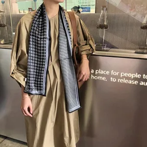 Dettaglio di sciarpa lunga in seta nera e bianca, design a doppio motivo, elegante accessorio.