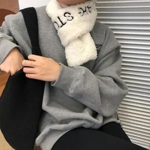 Detailed close-up shot of a cozy white fluffy plush winter neck warmer scarf worn with a grey sweatshirt.