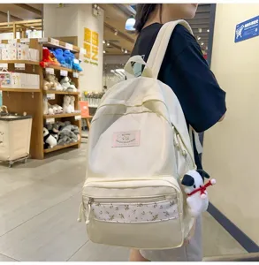 Detailed view of the white floral patchwork canvas backpack with cute puppy pendant in store scene.