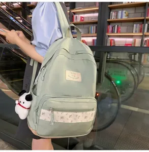 Detailed view of the light green casual backpack with floral patchwork and cute dog pendant in use.