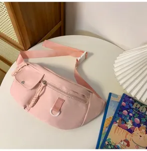 Détail de sac de poitrine en nylon rose, style croisé décontracté avec poche avant et anneau en D.