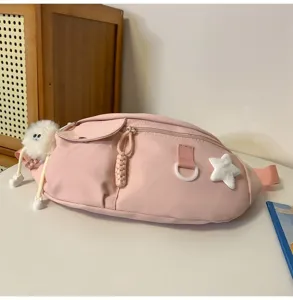 Détail de sac de poitrine en nylon rose avec pendentif monstre duveteux et étoile.