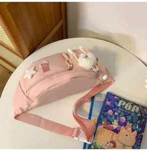 Sac de poitrine en nylon rose avec sangle réglable et pendentif duveteux pour le loisir.