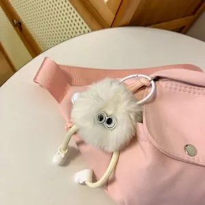 Détail d'un joli porte-clés moelleux blanc suspendu sur un élégant sac de poitrine rose.
