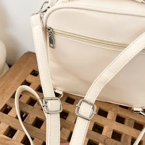 PU mini backpack detail featuring adjustable strap and silver metal buckle in white.