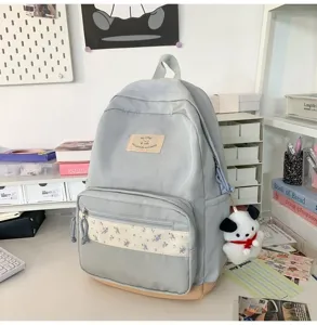 Detailed view of the light blue student backpack featuring floral patchwork and cute puppy charm.