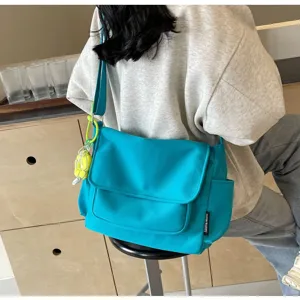 Λεπτομερής λήψη της casual μπλε τσάντας ταχυδρόμου από καμβά με καπάκι και πλαϊνή τσέπη.