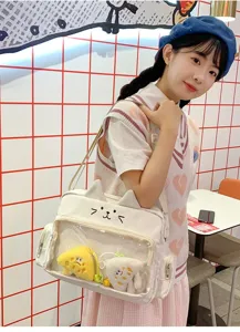 Cute cat ear ita bag detail, transparent window with plush charms, white crossbody bag.