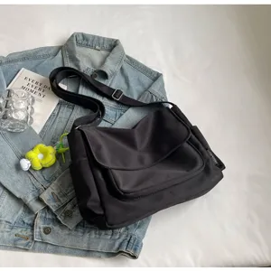 Μαύρη τσάντα ταχυδρόμου από καμβά με καπάκι, ρυθμιζόμενο λουρί και πλαϊνές τσέπες.