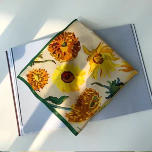 Gros plan sur le détail du foulard en soie tournesol artistique avec bordure verte.