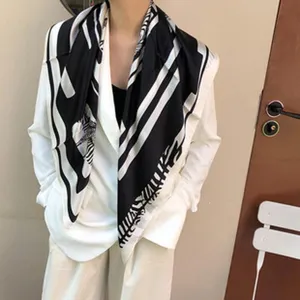 Detail van zwarte en witte zijden vierkante sjaal met patroon, elegante mode-accessoire.