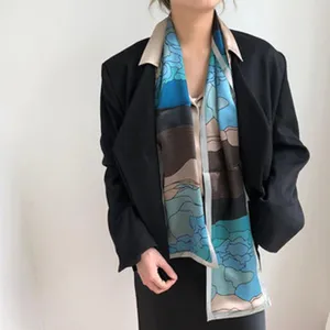 Gedetailleerd overzicht van een elegante smalle zijden sjaal met abstracte artistieke print in blauw.