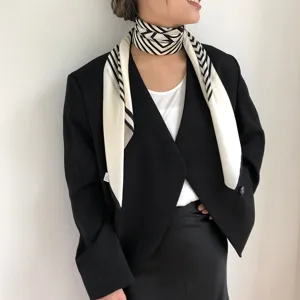Zijden vierkante sjaal detailopname, zwart-wit chevron patroon, elegante dames nek accessoire.