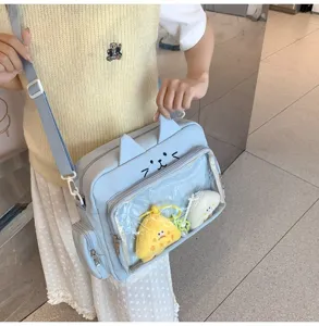 Detailed view of light blue cat ear ita bag with clear window showing cute plush charms.