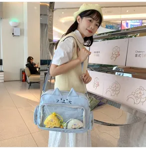 Cute cat ita bag with transparent display window and lovely plush pendants for daily wear.