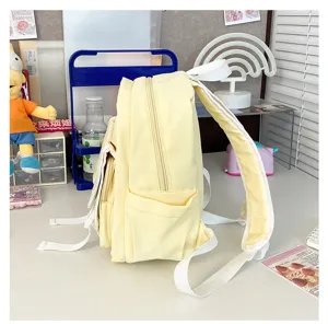 Detailed view of the cute yellow backpack side pocket, showing fabric texture and zippers.