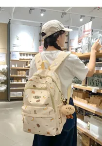 Detailaufnahme eines niedlichen Canvas-Rucksacks mit Cartoon-Print und Plüschtier-Anhänger.