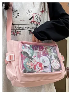 Detail shot of pink canvas ita bag with transparent window, pins and anime inserts for cosplay.