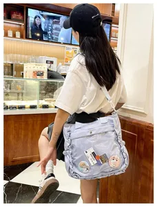 Detailed view of light blue Japanese anime ita bag with clear window and cute badges.