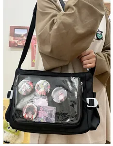 Detail shot of black canvas ita bag with transparent front pocket showing anime pin badges.