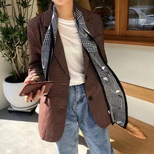 Vista dettagliata di una sciarpa di seta con stampa geometrica nera e bianca con blazer.