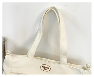 Detail de sac a main en toile blanche avec poignees robustes et design minimaliste elegant.