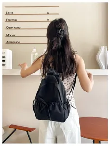Gedetailleerd uitzicht van zwarte nylon rugzak met stijlvolle strik en casual stijl.