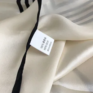Gedetailleerd overzicht van luxe moerbeizijden sjaal met handgerolde randen en fijne textuur