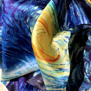 Close-up detail of artistic starry sky print silk scarf, showcasing smooth texture and vibrant blue.