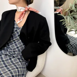 Detailansicht eines stilvollen Seidenschals, kombiniert mit einem schwarzen Blazer und Kleid.