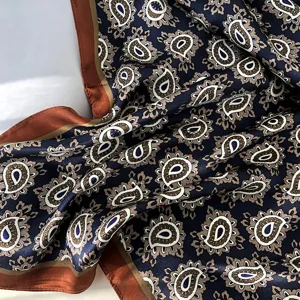 Close-up detail van de luxe paisley zijden sjaal met klassieke blauwe en bruine patronen erin.