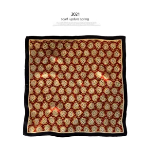 Gedetailleerd overzicht van de paisley zijden sjaal met rode print en zwarte rand voor lente.