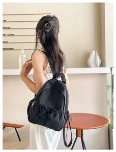 Gedetailleerd overzicht van zwarte nylon rugzak met scrunchie handvat en leuke strik.