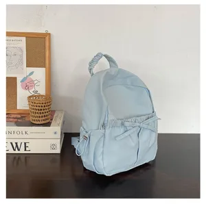 Gedetailleerd overzicht van een lichtblauwe nylon rugzak met schattige strik en gerimpeld handvat.