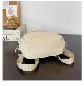 Gedetailleerd overzicht van de beige nylon rugzak met zachte textuur en een mooie strik.