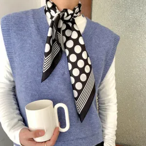 Gros plan détaillé d'un foulard en soie classique à pois noirs et blancs porté élégamment.
